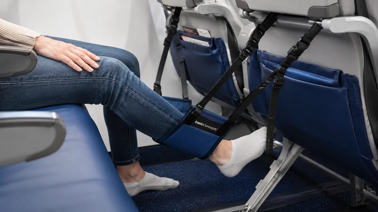 Traveler doing ankle circles and calf raises while feet rest in a foot hammock on a long flight