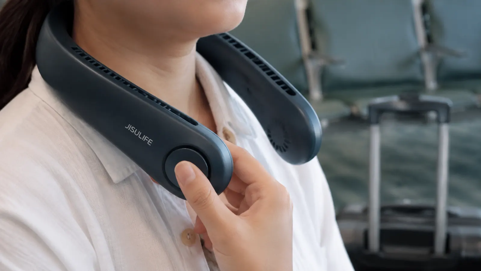 Close-up of hands adjusting the JISULIFE neck fan's speed button while wearing it around the neck